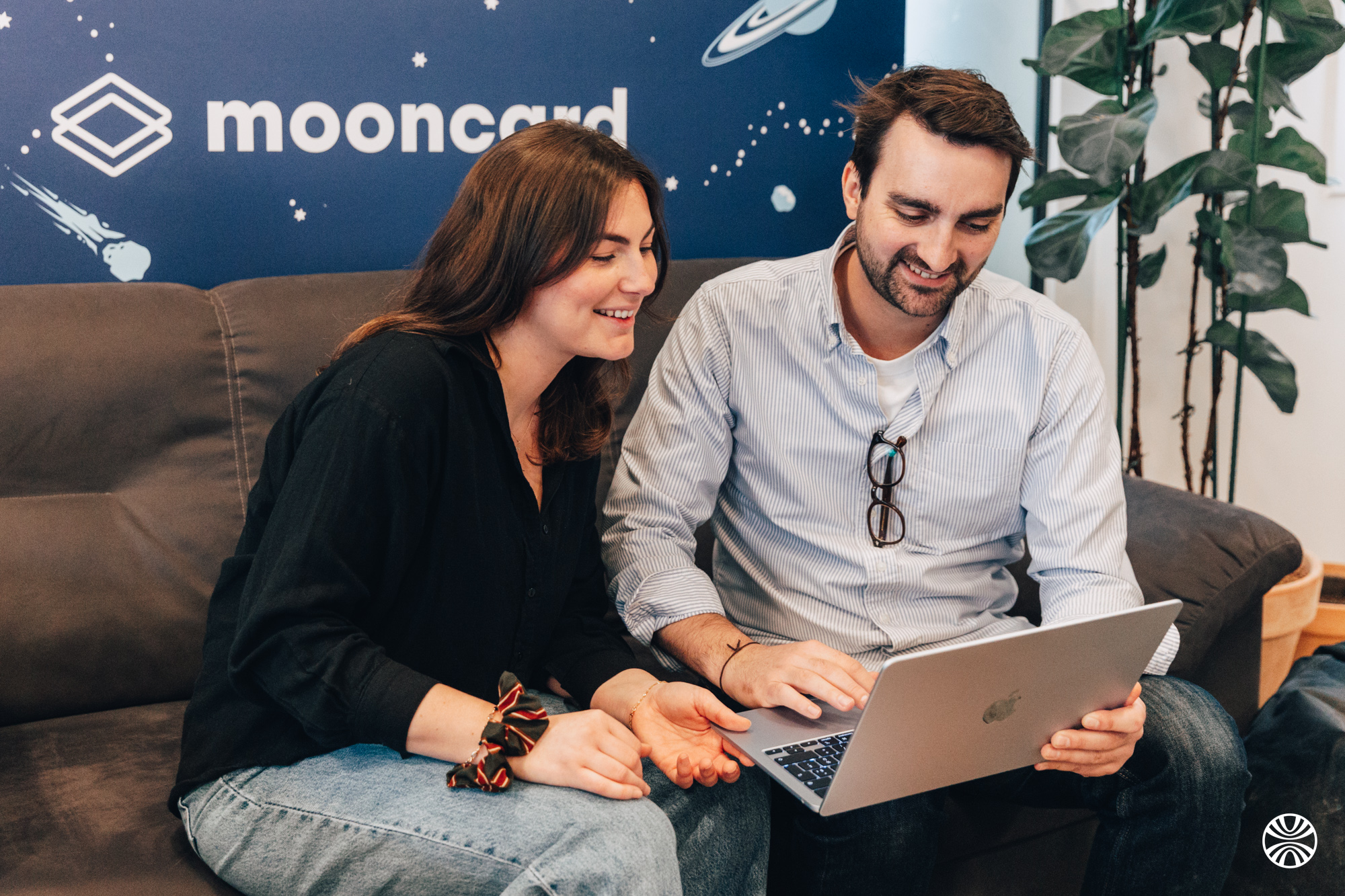 Deux collègues Mooncard échangeant sur un canapé devant le mur Mooncard