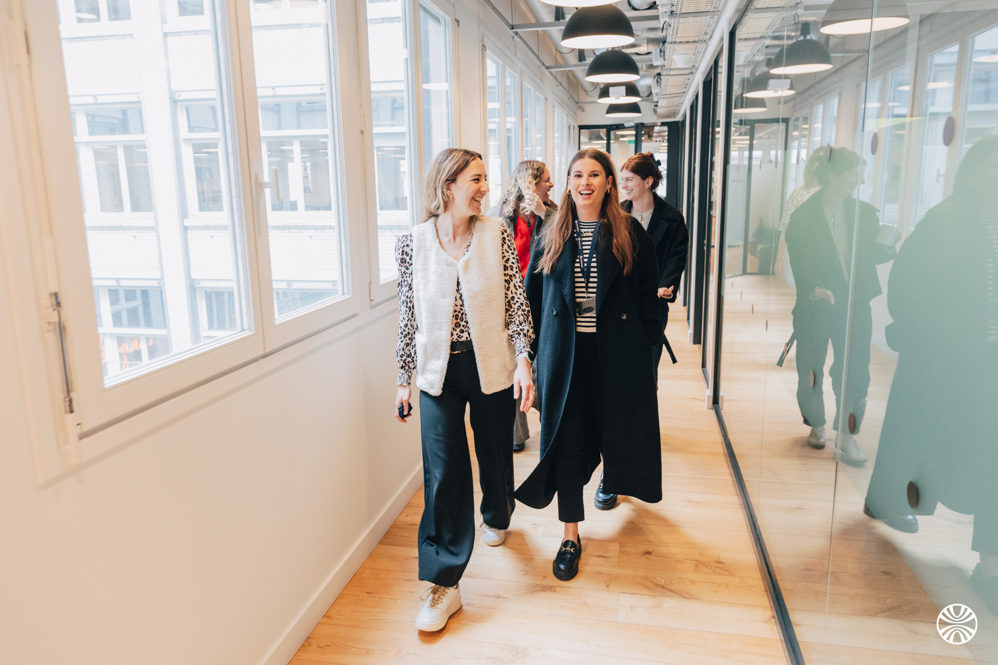 Collaborateurs Mooncard marchant ensemble dans le couloir lumineux des bureaux
