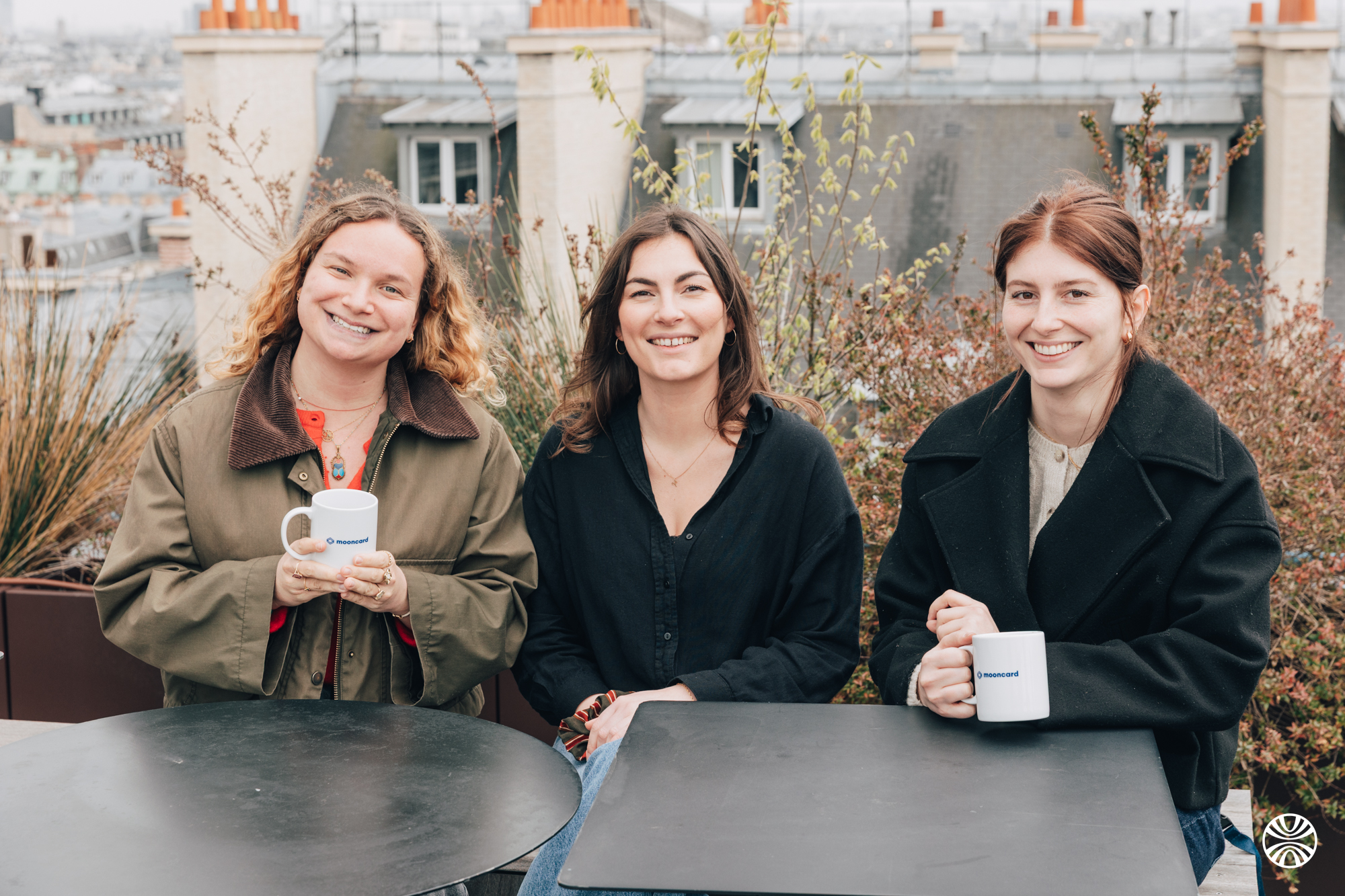 Trois collaboratrices Mooncard souriantes sur la terrasse des bureaux