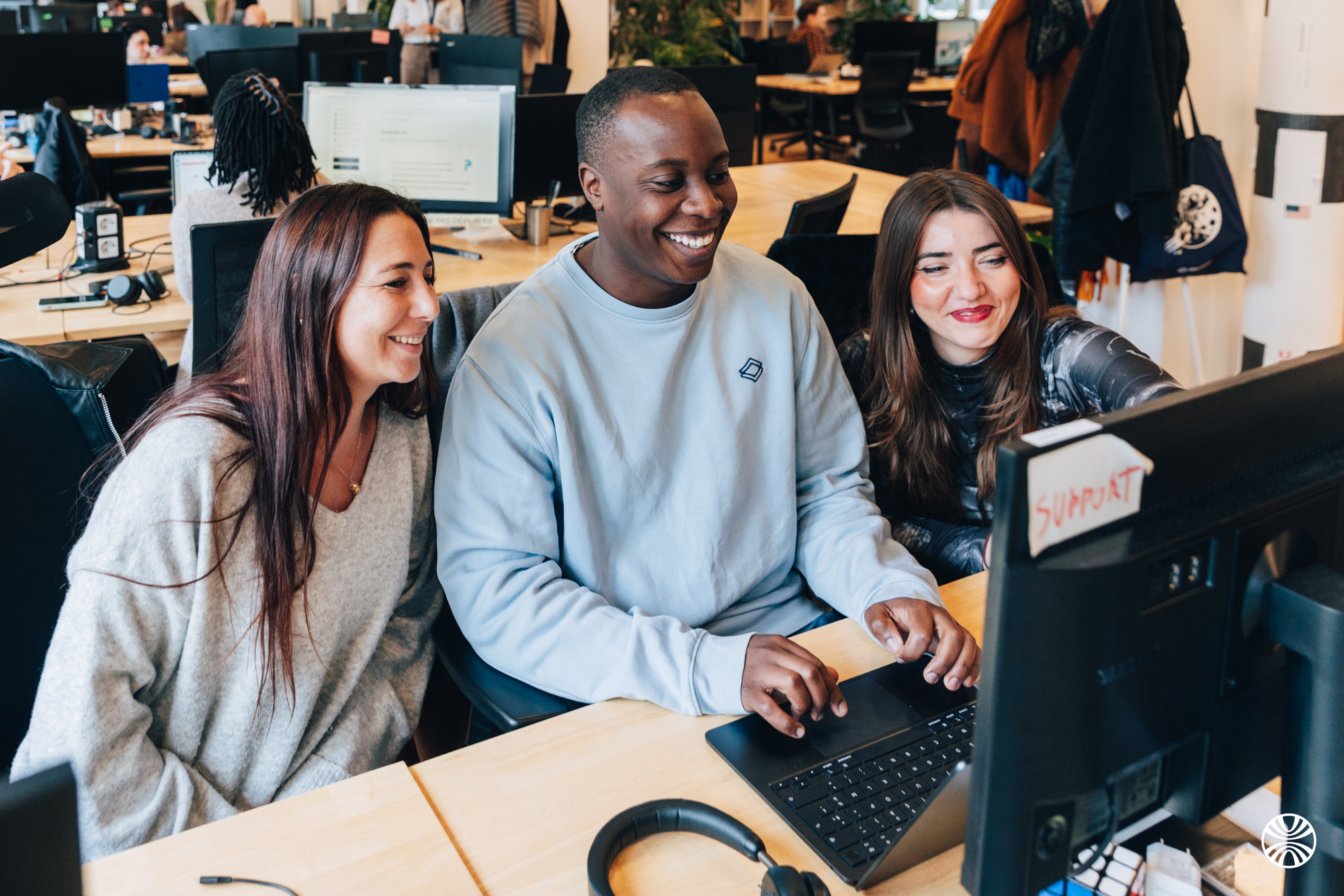 Trois collègues Mooncard qui sourient autour d’un ordinateur